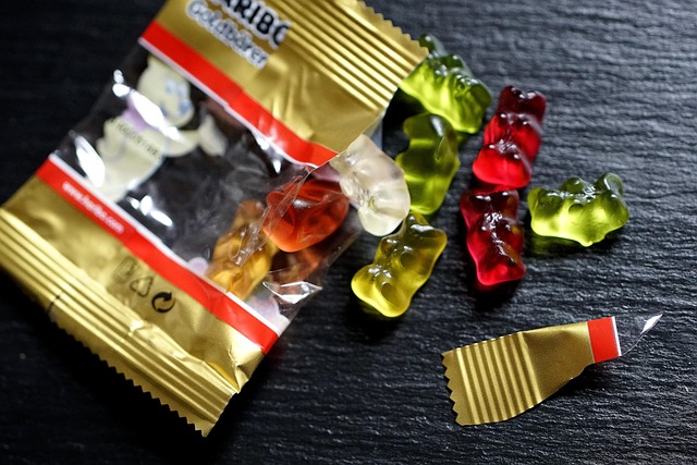 An opened bag of colorful gummy bear candies spilled on stone