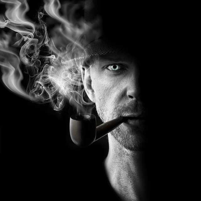A man smoking a pipe with thick smoke rising