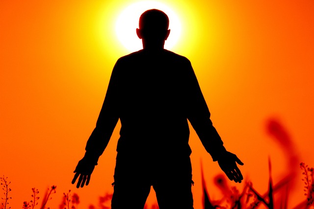 Silhouette of a person standing outdoors in front of a bright sun
