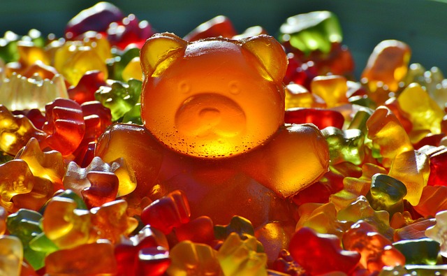 A large orange gummy bear sitting on colorful gummy bears
