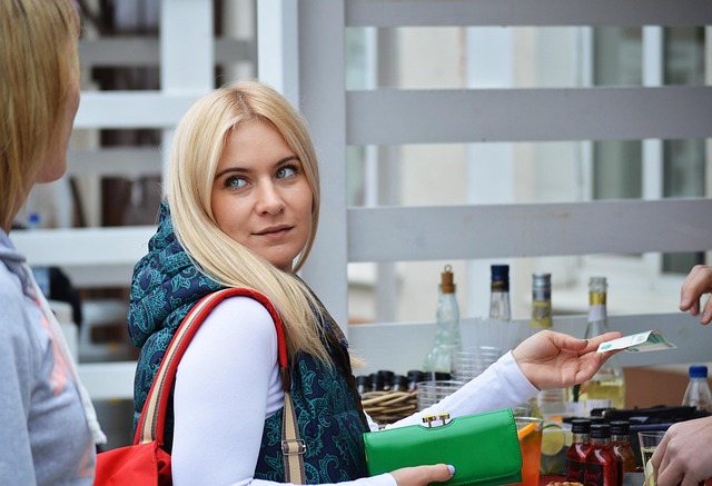 A blonde woman handing cash to a vendor at a counter