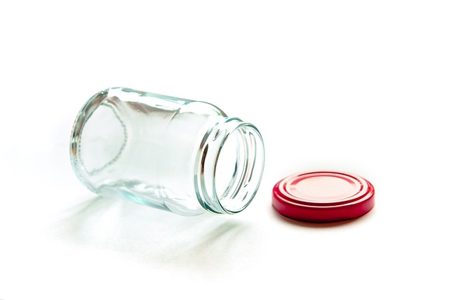 An empty glass jar lying on its side with a red lid