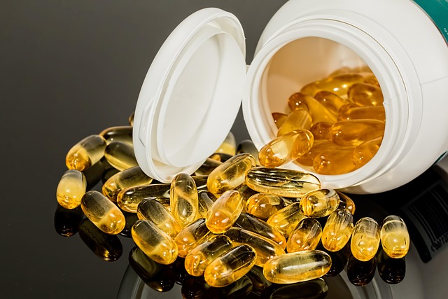 Yellow softgel capsules spilling out of a white supplement bottle