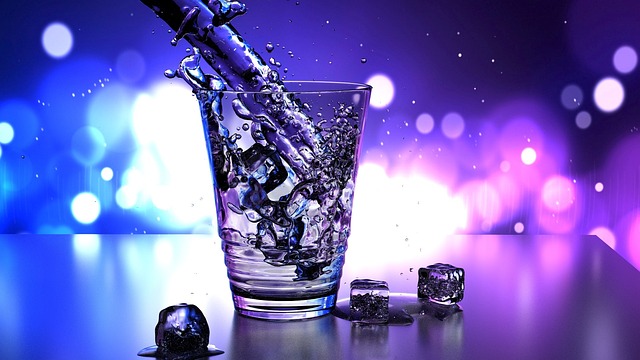 Water splashing into a glass with ice cubes