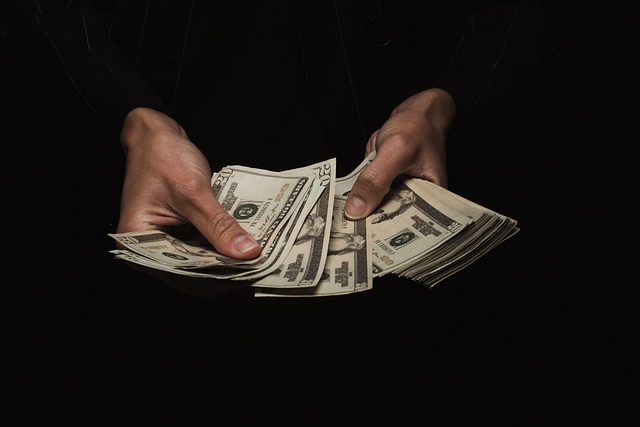 Hands holding and counting a stack of US dollar bills